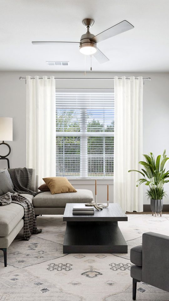 a living room with a ceiling fan and a couch at The La Ventana at Canyon West Apartments