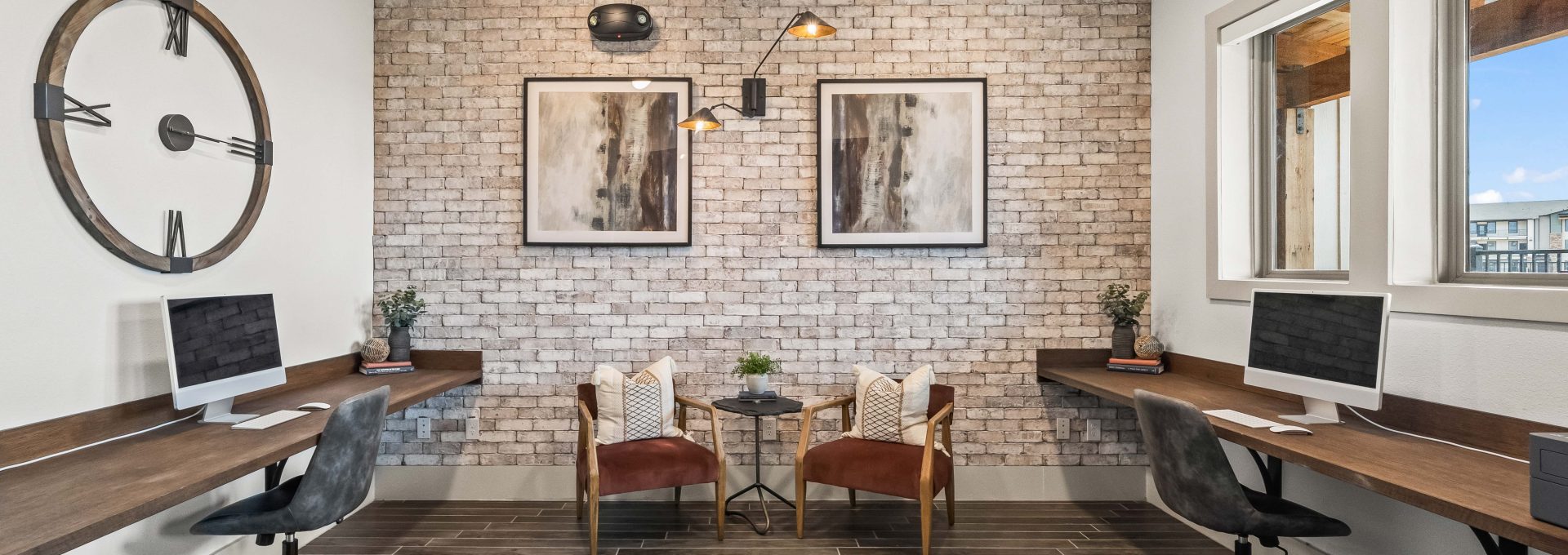 a modern office with a brick wall and wooden desk at The La Ventana at Canyon West Apartments